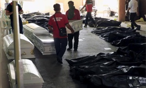 ○ヴァレンズエラ市ホールで、工場火災の遺体バッグそばに棺桶を運んでいる.jpg